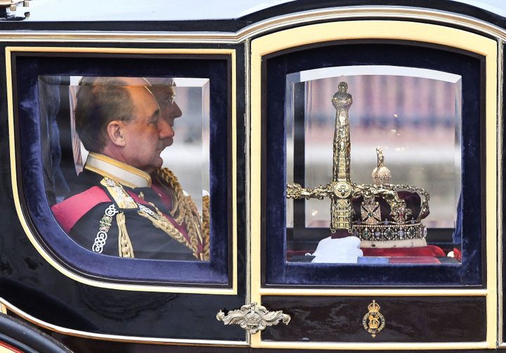 The state regalia, the sword of state, imperial state crown and the cap of maintainance are transferred in the Queen Alexandra's State Coach from Buckingham Palace to the Houses of Parliament.