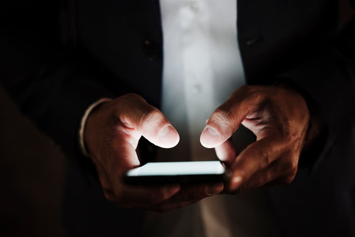 Una persona, manejando su teléfono móvil.