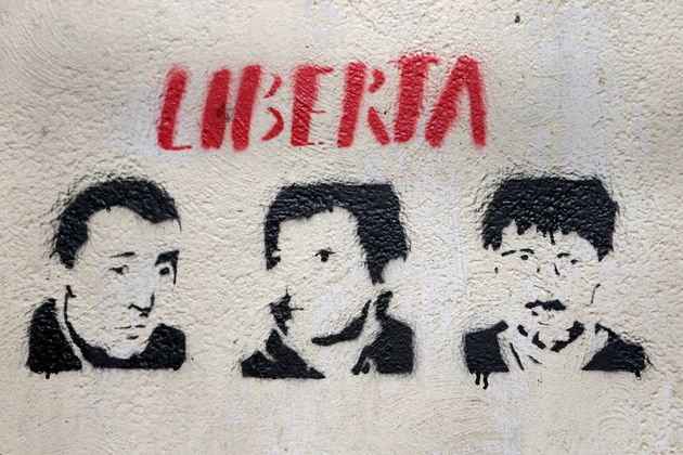 Une photographie prise le 14 mars 2022 à Bastia d'un graffiti à l'éfigie des trois hommes impliqués dans le commando du préfet Erignac, Yvan Colonna (à gauche), Alain Ferrandi (au centre) et Pierre Alessandri (à droite).