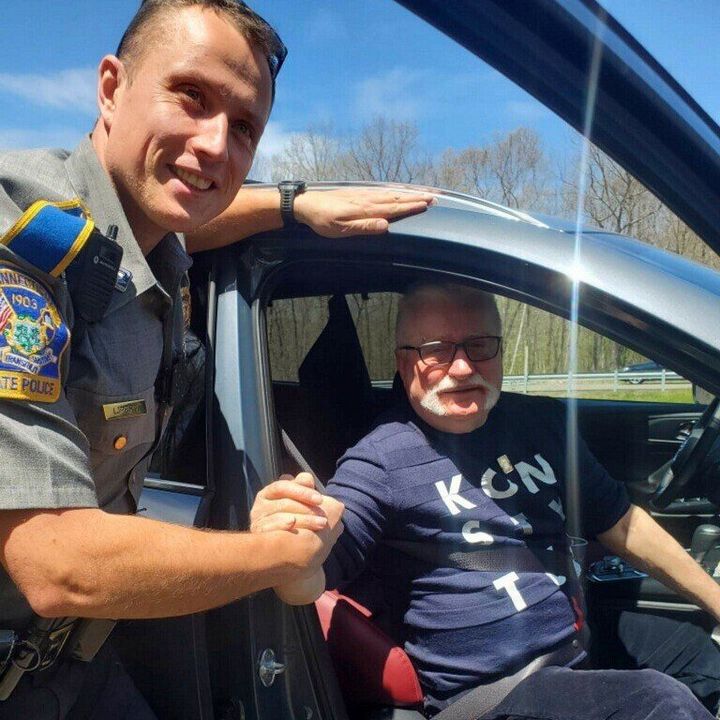 In this photo provided by the Connecticut State Police, Trooper Lukasz Lipert shakes hands with former Polish President Lech Walesa on Interstate 84 in Tolland, Conn., on Wednesday, May 11, 2022. (Connecticut State Police via AP)