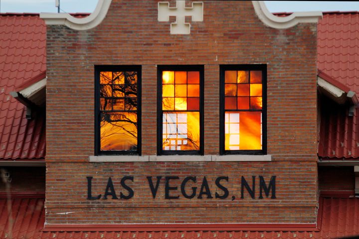 Reddened by wildfire smoke, the sun is seen reflected off windows at the train station in Las Vegas, N.M., on Saturday, May 7, 2022. (AP Photo/Cedar Attanasio)