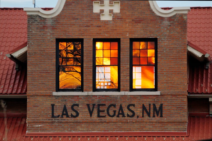 Reddened by wildfire smoke, the sun is seen reflected off windows at the train station in Las Vegas, N.M., on Saturday, May 7, 2022. (AP Photo/Cedar Attanasio)