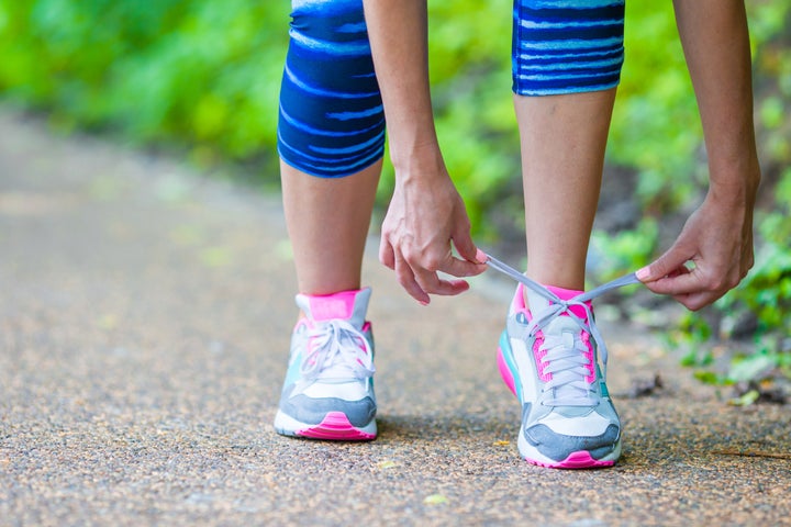 Closeup on shoe of athlete runner woman feet running on road