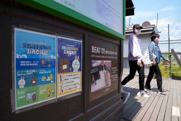People pass by posters reminding precautions against the coronavirus at the Imjingak Pavilion in Paju, South Korea, near the border with North Korea, Sunday, May 15, 2022. North Korea has confirmed 15 more deaths and hundreds of thousands of additional patients with fevers as it mobilizes more than a million health and other workers to try to suppress the country's first COVID-19 outbreak, state media reported Sunday. The signs read "The precautions against the coronavirus 19." (AP Photo/Ahn Young-joon)