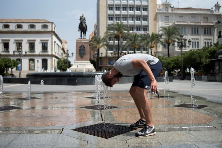 Un hombre se refresca en una fuente pública en Córdoba.