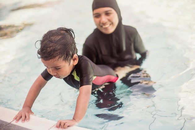Une femme portant un burkini entraîne son enfant à nager dans un bassin (photo