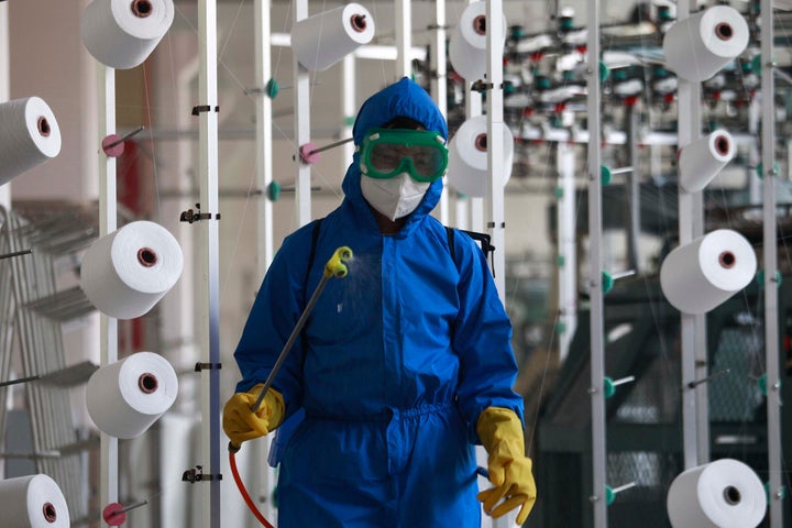 An employee of Songyo Knitwear Factory in Songyo district disinfects the work floor in Pyongyang, North Korea, Wednesday, May 18, 2022, after Kim Jong Un said Tuesday his party would treat the country's outbreak under the state emergency. (AP Photo/Jon Chol Jin)