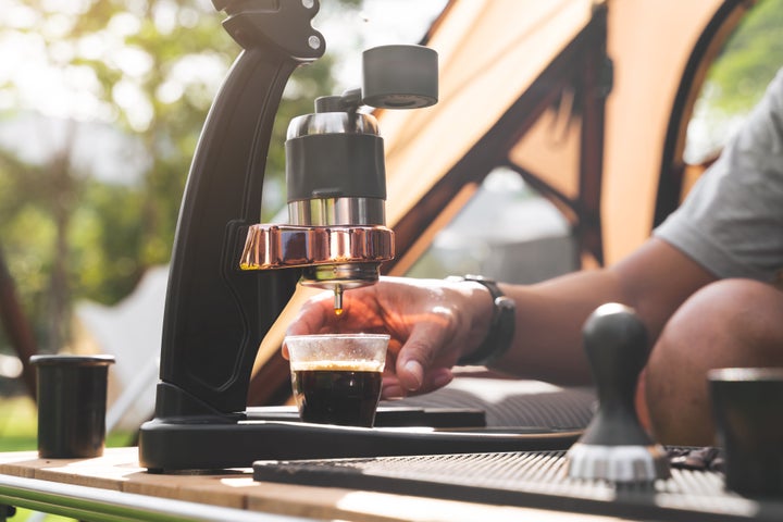 Crop man making fresh espresso coffee in front the tent in morning