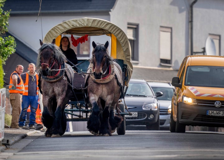 Horse farmer Stephanie Kirchner steers her coach on the main road through her hometown Schupbach near Limburg, Germany, Thursday, May 19, 2022. Since the beginning of the war in the Ukraine causing rising gas prices Kirchner uses the coach or rides a horse to a small stud farm where she works whenever possible. (AP Photo/Michael Probst)