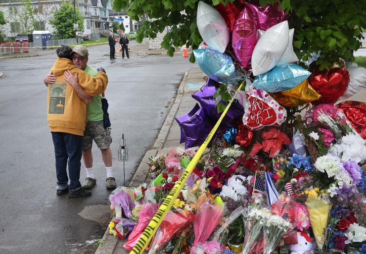 BUFFALO, NEW YORK - MAY 18: People visit a makeshift memorial set up outside the Tops supermarket on May 18, 2022 in Buffalo, New York. A gunman opened fire at the store on Saturday, killing 10 people and wounding three others. Police say it's being investigated as a racially motivated hate crime. (Photo by Scott Olson/Getty Images)