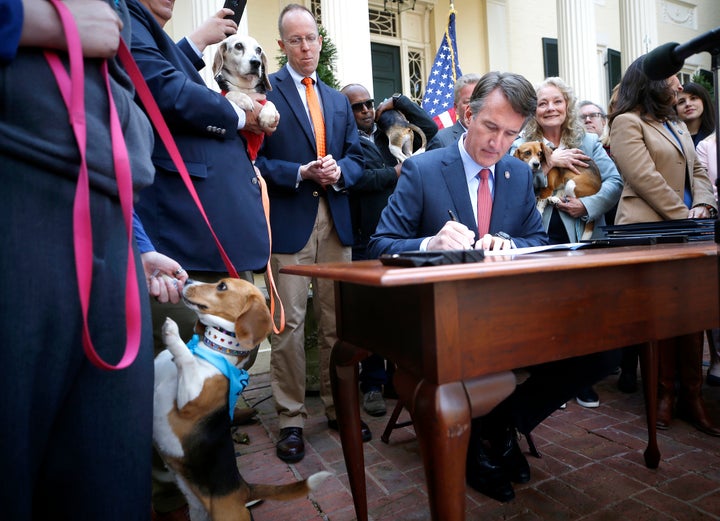 Emily Neal feeds her adopted dog Tannis a treat as Virginia Gov. Glenn Youngkin signs five bills to penalize animal cruelty and prohibit the sale of dogs or cats for experimental purposes on Monday, April 4, 2022 in Richmond, Virginia.