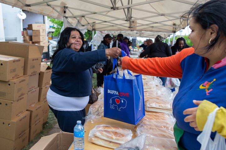 Yvonne King, left, hands out bags of breads to community members near the Tops Friendly Market, Tuesday, May 17, 2022, in Buffalo, New York.