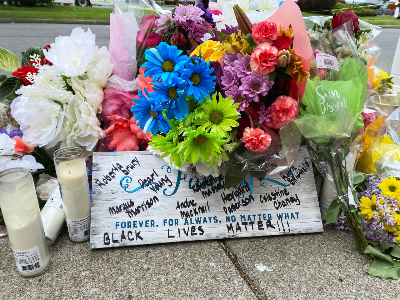 Flowers left outside of Tops Friendly Market and a sign with the names of the 10 people who were killed in what authorities have described as a “racially-motivated” shooting at a Buffalo, New York, on May 14.
