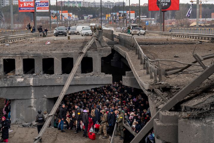Des Ukrainiens se pressent sous un pont détruit alors qu'ils tentent de traverser la rivière Irpin dans la périphérie de Kiev, en Ukraine, le 5 mars 2022.