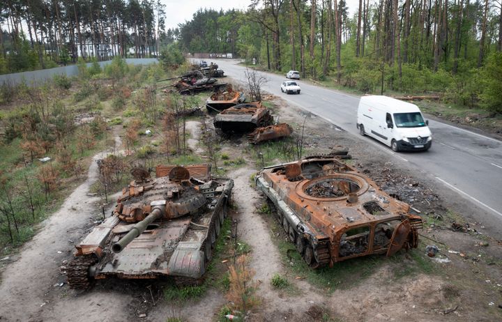 Des voitures passent à côté de chars russes détruits lors d'une récente bataille contre les Ukrainiens dans le village de Dmytrivka, près de Kiev, en Ukraine, le 23 mai 2022. 