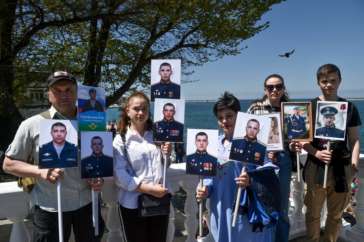 Des proches de militaires décédés au cours de l'opération militaire spéciale russe dans le Donbass posent pour une photo tenant des portraits de soldats russes tués lors d'un combat en Ukraine après avoir assisté à la marche du régiment immortel dans une rue marquant le 77e anniversaire de la fin de la Seconde Guerre mondiale, en Sébastopol, Crimée, 9 mai 2022.