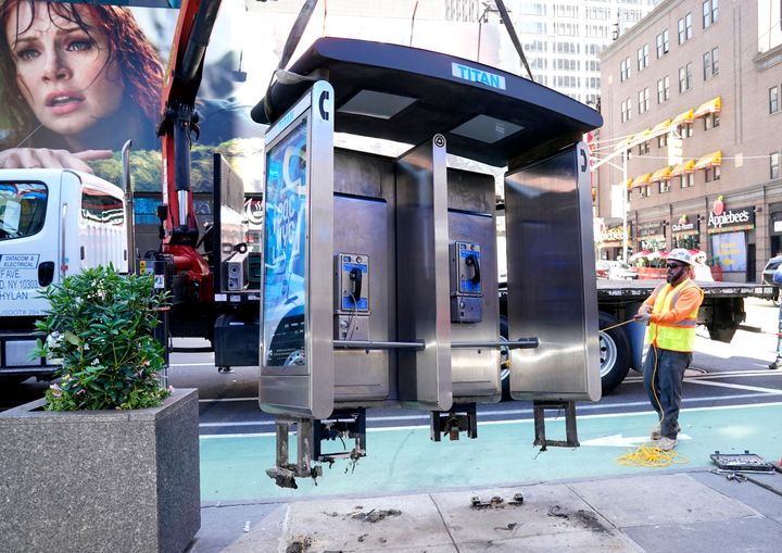 Workers remove the final New York City payphone near Seventh Avenue and 50th Street in Midtown Manhattan on Monday.
