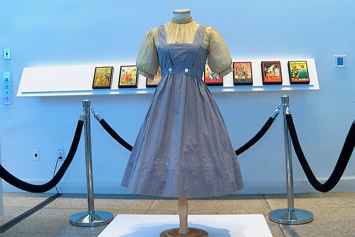 A blue and white checked gingham dress, worn by Judy Garland in the "Wizard of Oz," hangs on display, Monday, April 25, 2022, at Bonhams in New York. A judge has blocked the planned auction of the dress, scheduled in Los Angeles on Tuesday, May 24 put up for sale by Catholic University of America after being rediscovered there in a shoebox during a renovation. Auctioneer Bonhams listed a presale estimate of $800,000 to $1.2 million for the dress before it was withdrawn. (AP Photo/Katie Vasquez)