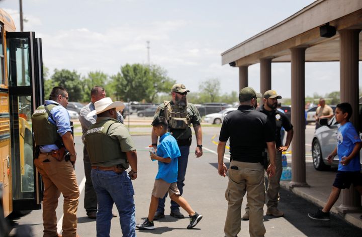 Children get on a school bus as law enforcement personnel guard the scene of a shooting near Robb Elementary School in Uvalde, Texas, on Tuesday.