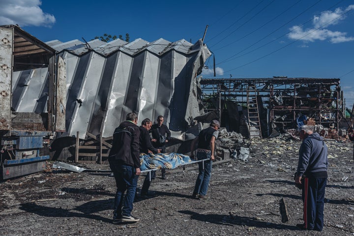 BAKHMUT, UKRAINE - MAY 24: Two funeral workers carry the body of a civilian killed by a Russian shell in a building materials warehouse in Bakhmut, Donetsk Oblast, Ukraine, 24 May 2022. (Photo by Diego Herrera Carcedo/Anadolu Agency via Getty Images)