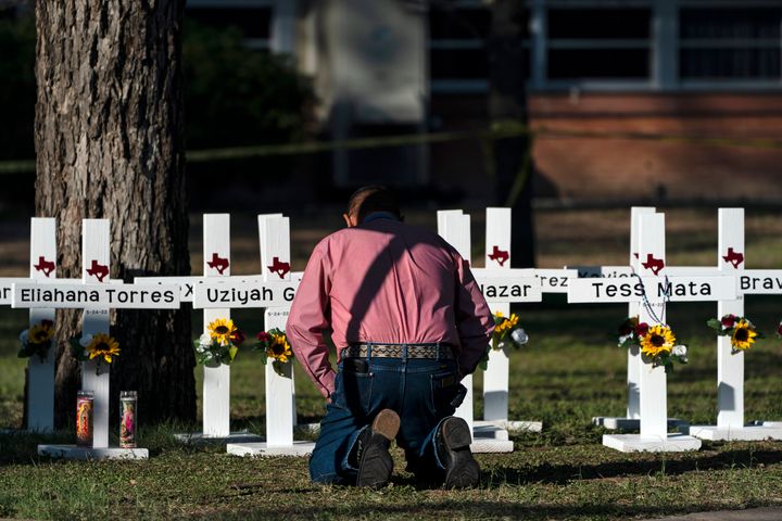 The Rev. Daniel Myers kneels in front of crosses bearing the names of Tuesday's shooting victims while praying for them at Robb Elementary School in Uvalde, Texas.