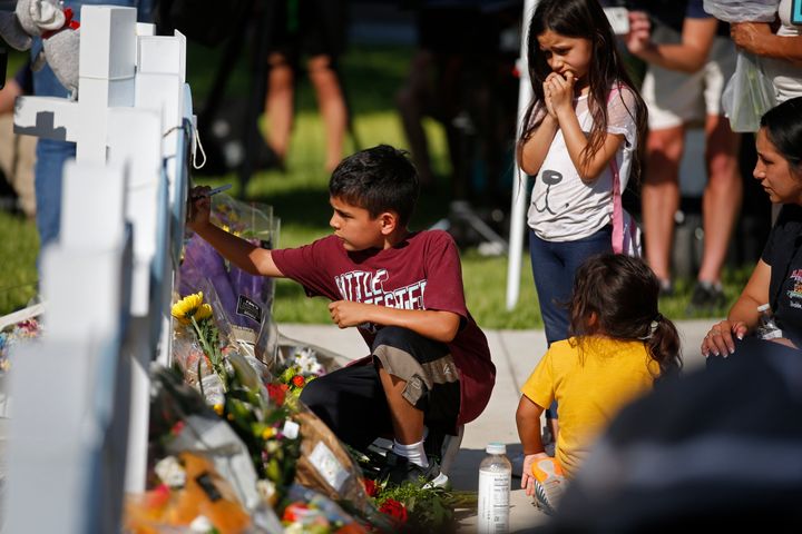 A child writes a message on a cross at a memorial site for the victims killed in this week's elementary school shooting in Uvalde, Texas.