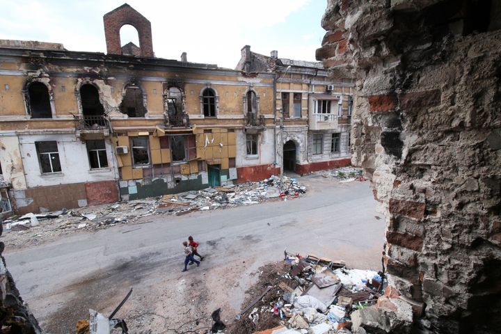Children walk among buildings destroyed during fighting in Mariupol, in territory under the government of the Donetsk People's Republic, eastern Ukraine, on May 25, 2022.