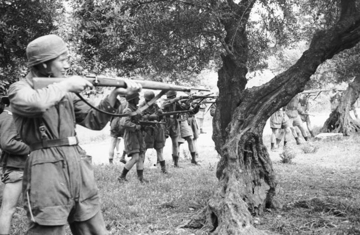 Το εκτελεστικό απόσπασμα σε θέση βολής στους ελαιώνες έξω από το Κοντομαρί. Ο στρατιώτης που μειδιά στο προσκήνιο, εντοπίστηκε μετά από πολλά χρόνια κατά τις διακοπές του στην Κρήτη από ξενοδόχο που τον αναγνώρισε. Όταν του έδειξε τις φωτογραφίες, παραδέχτηκε ότι ήταν αυτός και κυνικά απάντησε ότι εκτελούσε εντολές και έκτοτε δεν εθεάθη ξανά από τον Έλληνα ξενοδόχο στην περιοχή