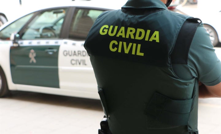 Un agente de la Guardia Civil, de espaldas junto a un coche patrulla
