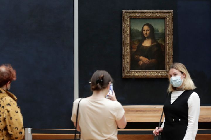 Visitors pose in front of Leonardo da Vinci's Mona Lisa in the Louvre museum, Wednesday, May, 19, 2021 in Paris. A man seemingly disguised as an old woman in a wheelchair threw a piece of cake at the glass protecting the Mona Lisa on May 29, 2022, at the Louvre Museum and shouted at people to think of planet Earth. 