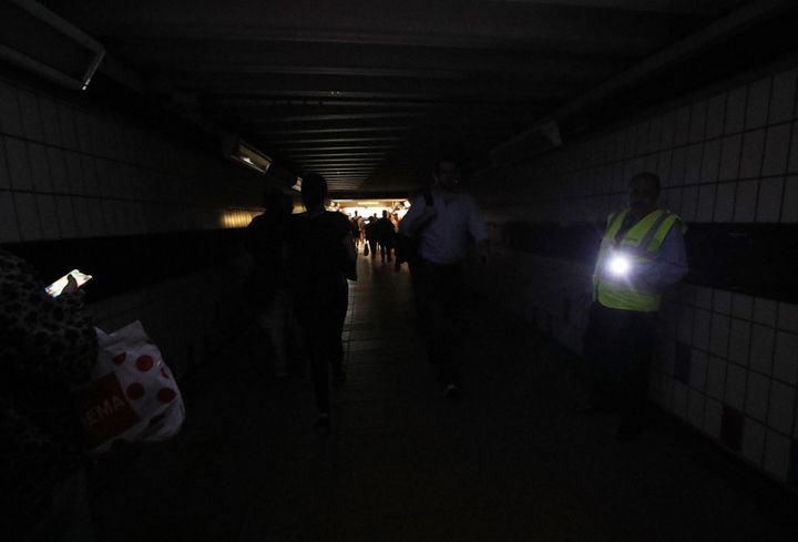 People walk in complete darkness at Clapham Junction station in London during a power cut in 2019.