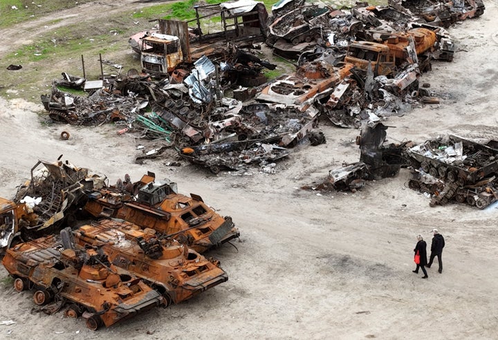 People walk past the wreckage of military vehicles in Bucha, on the outskirts of Kyiv, Ukraine, on April 30, 2022. Representatives of a group of nations working together to investigate war crimes committed since Russia's invasion of Ukraine are meeting May 31 in The Hague amid ongoing calls for those responsible for atrocities to be brought to justice.