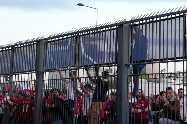 Des personnes grimpant sur des grilles entourant le Stade de France avant la finale de la Ligue des champions entre Liverpool et le Real Madrid, à Saint-Denis, le 28 mai 2022.