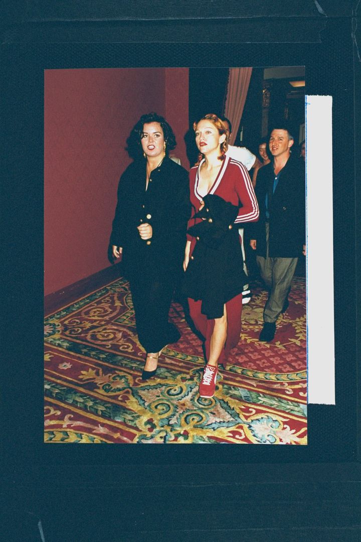Madonna wearing low-cut maroon cotton Adidas dress with a side-slit and matching platform Puma sneakers, arriving with Rosie O'Donnell at the premiere party for the film "Sleepless in Seattle."
