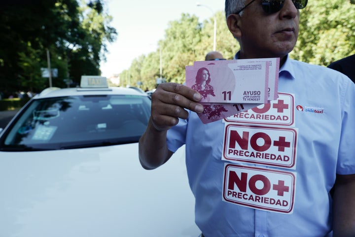 Un manifestante enseña billetes falsos con la cara de Ayuso, durante la manifestación.