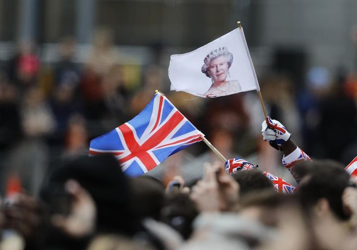 A man waves a British union flag and a flag bearing the image of Britain's Queen Elizabeth II ahead of the annual Commonwealth Day service at Westminster Abbey in London on March 9, 2020. 