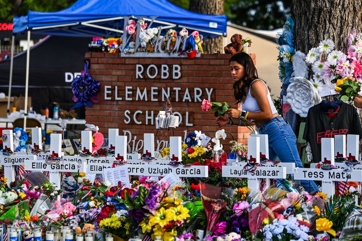 Une fillette dépose des fleurs sur un mémorial de fortune à la Robb Elementary School à Uvalde, Texas, le 28 mai 2022. 