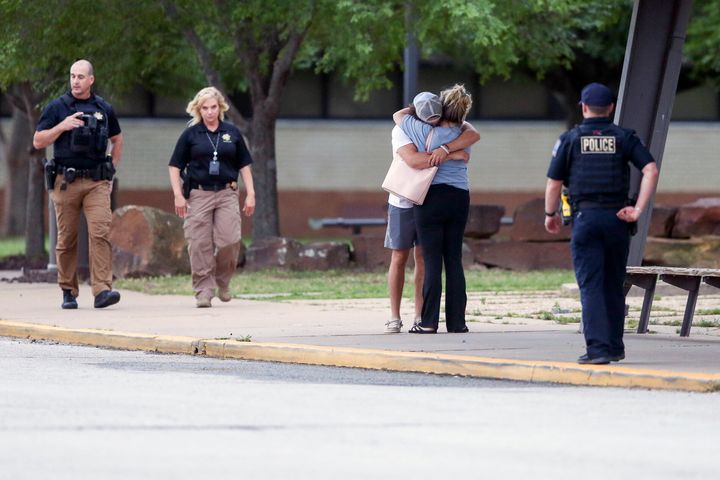 Two people hug outside Memorial High School where people were evacuated from the scene of a shooting at a Tulsa medical building.