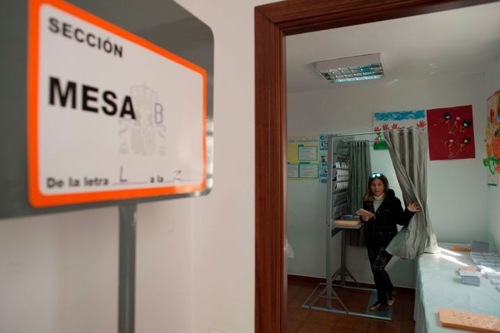 Una mujer sale de una cabina para elegir su voto en un colegio electoral de Zahara De la Sierra (Cádiz)