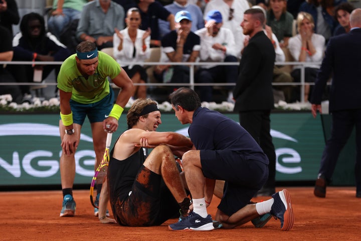Zverev en el suelo, es atendido por un médico mientras Nadal se interesa por él