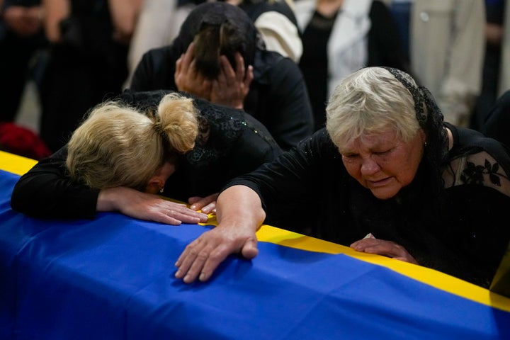 The mother, right, and sister of Army Col. Oleksander Makhachek mourn over the coffin with his remains during a funeral service in Zhytomyr, Ukraine, Friday, June 3, 2022.