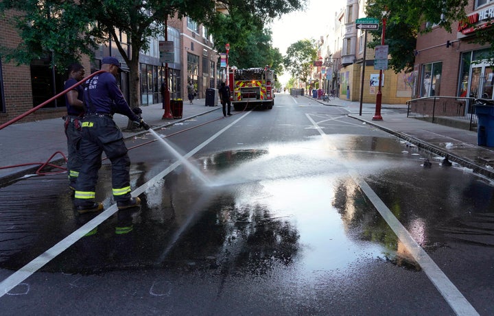 A Philadelphia firefighter washes blood off the sidewalk at the scene of a fatal overnight shooting on South Street in Philadelphia on Sunday.