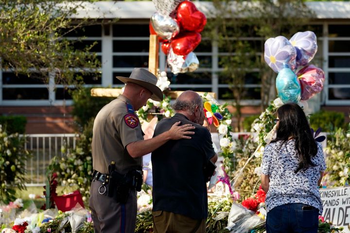 A man is comforted by a Texas Department of Public Safety officer at a memorial outside Robb Elementary School on Friday in Uvalde, Texas.