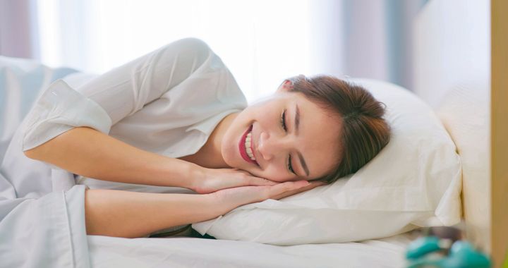 asian woman sleep well with smile on bed and keep sleeping