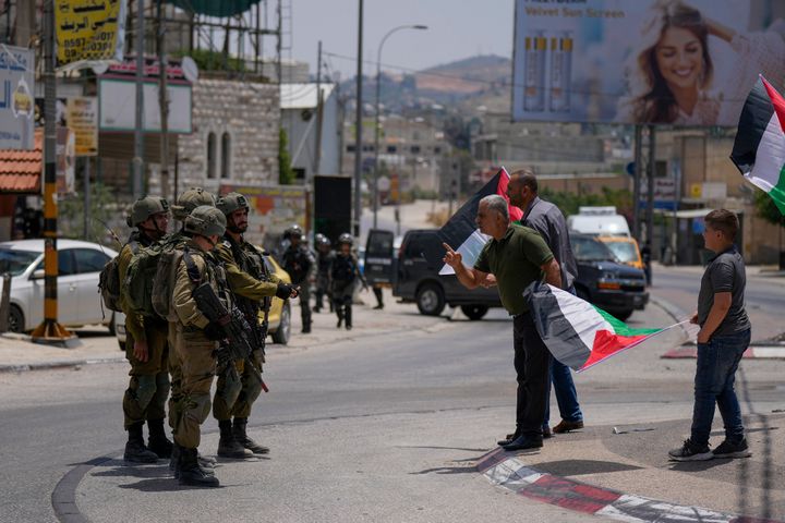 Ένας Παλαιστίνιος διαφωνεί με Ισραηλινούς στρατιώτες κατά τη διάρκεια διαδήλωσης κατά της αφαίρεσης των παλαιστινιακών σημαιών από Εβραίους εποίκους στο σημείο ελέγχου Hawara, κοντά στην πόλη Nάμπλους στη Δυτική Όχθη, Παρασκευή, 27 Μαΐου 2022.