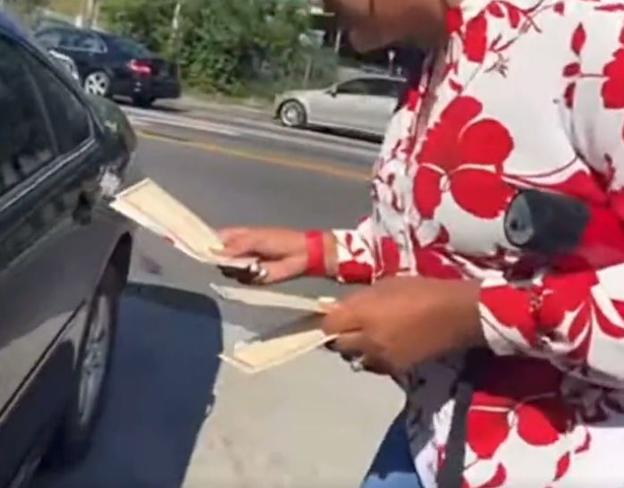 Volunteer hands out a $25 fuel voucher with a Herschel Walker campaign flyer to a driver who was waiting to obtain gas in Atlanta.