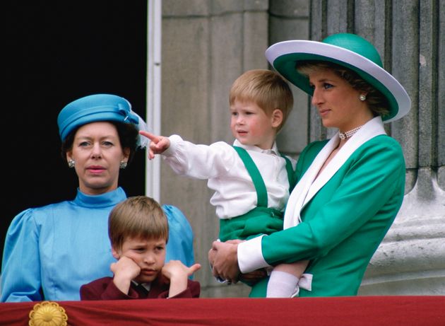 バッキンガム宮殿のバルコニーで撮影された写真。ウィリアム王子も両手でほおづえをつき、不機嫌な様子。右は母のダイアナ元妃と、抱っこされる弟のヘンリー王子（1988年6月撮影）
