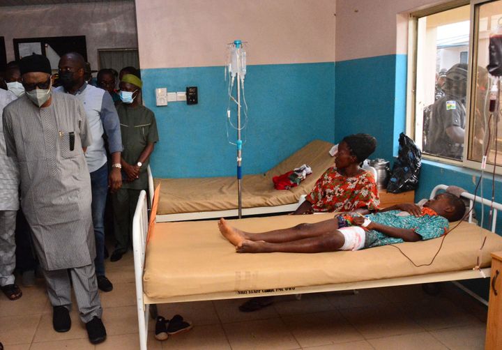 State officials walk past injured victims on hospital beds being treated for wounds following an attack by gunmen at St. Francis Catholic Church in Owo town, southwest Nigeria on June 5, 2022.