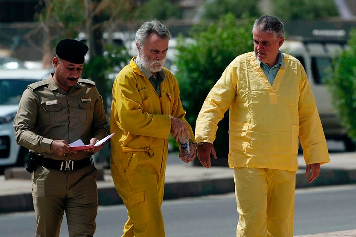 Volker Waldmann, right, and Jim Fitton, center, are seen handcuffed as they walk to a courtroom in Baghdad, Iraq, on May 22. The pair was accused of smuggling ancient shards out of Iraq. Fitton was sentenced to 15 years on Monday.