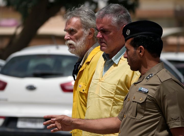 Jim Fitton, left, and Volker Waldmann, center, are seen handcuffed while being escorted outside a Baghdad courtroom. Waldmann was found not to have had criminal intent in the case and will be released.